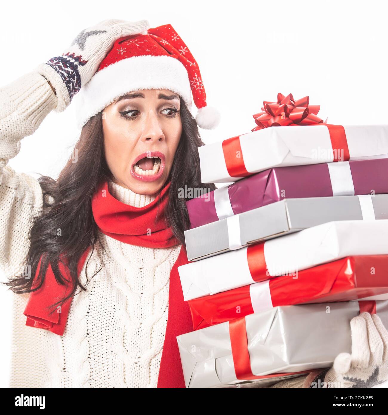 Une femme désespérée regarde les cadeaux de Noël avec une expression horrifiée sur son visage. Banque D'Images