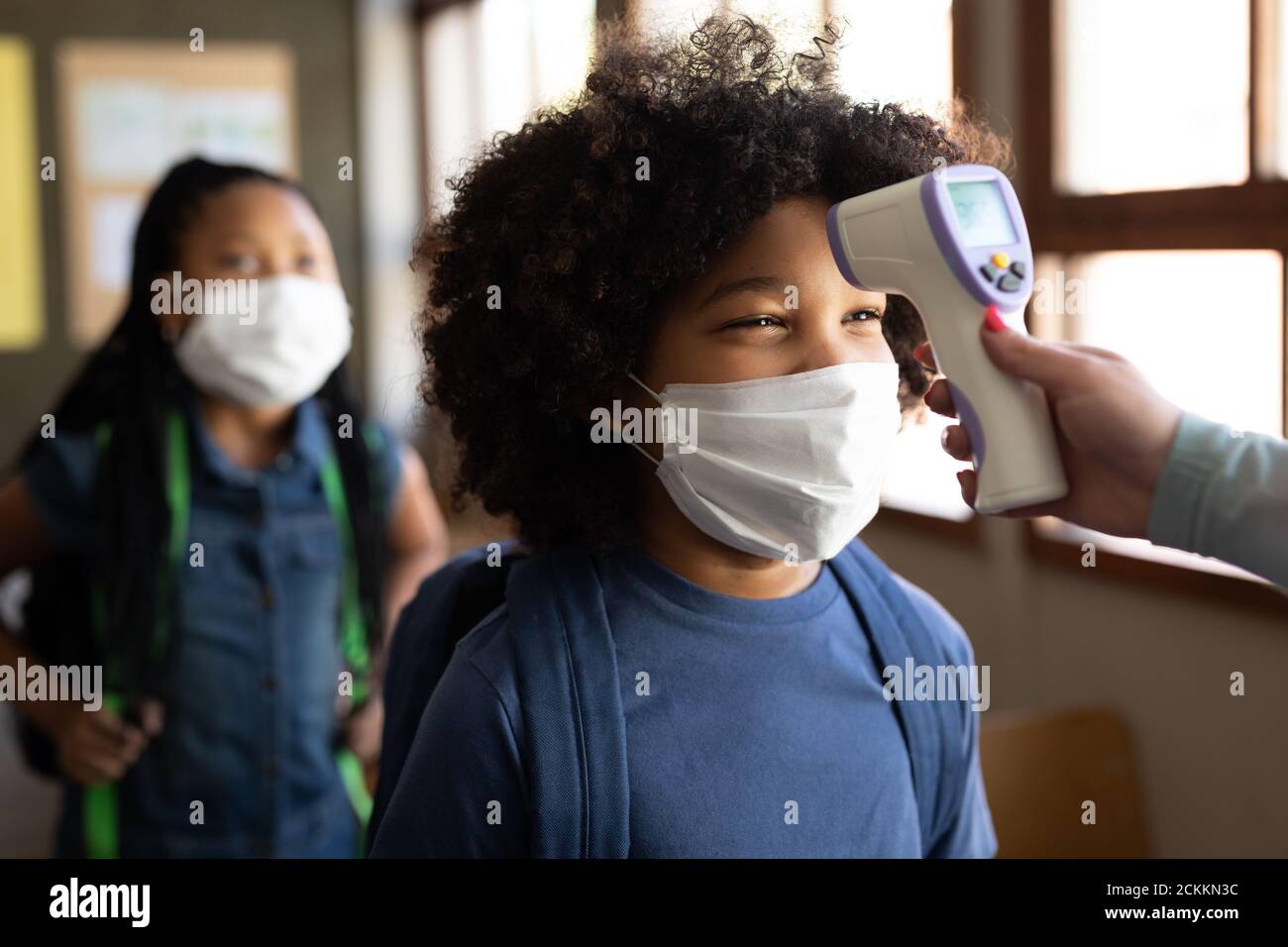 Garçon portant un masque facial obtenant sa température mesurée en classe à l'école Banque D'Images