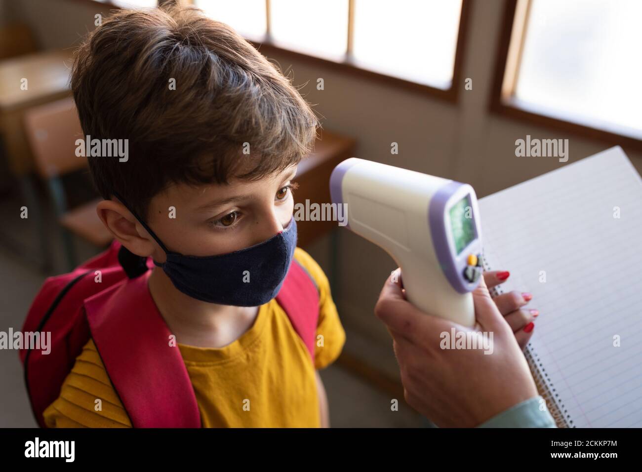 Garçon portant un masque facial obtenant sa température mesurée en classe à l'école Banque D'Images