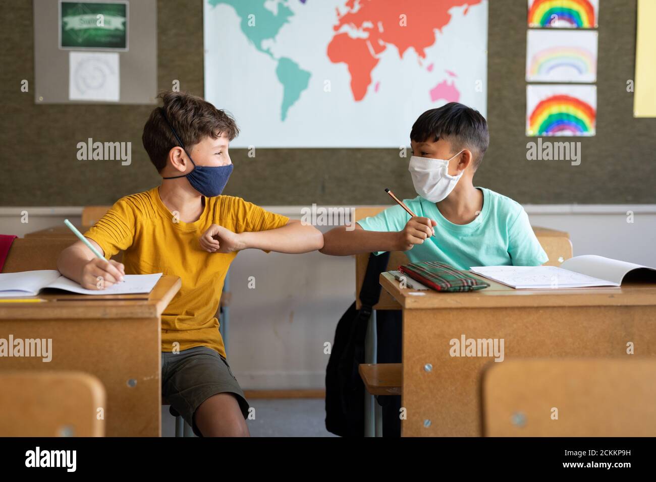 Deux garçons portant un masque facial se saluent l'un l'autre en touchant coudes à l'école Banque D'Images