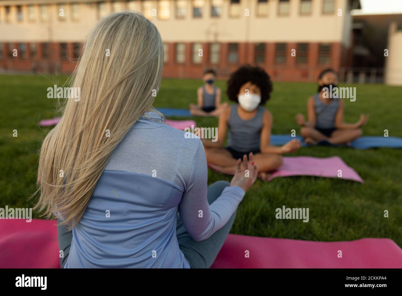 Une enseignante et un groupe d'enfants portant un masque facial s'exécutant yoga dans le jardin Banque D'Images