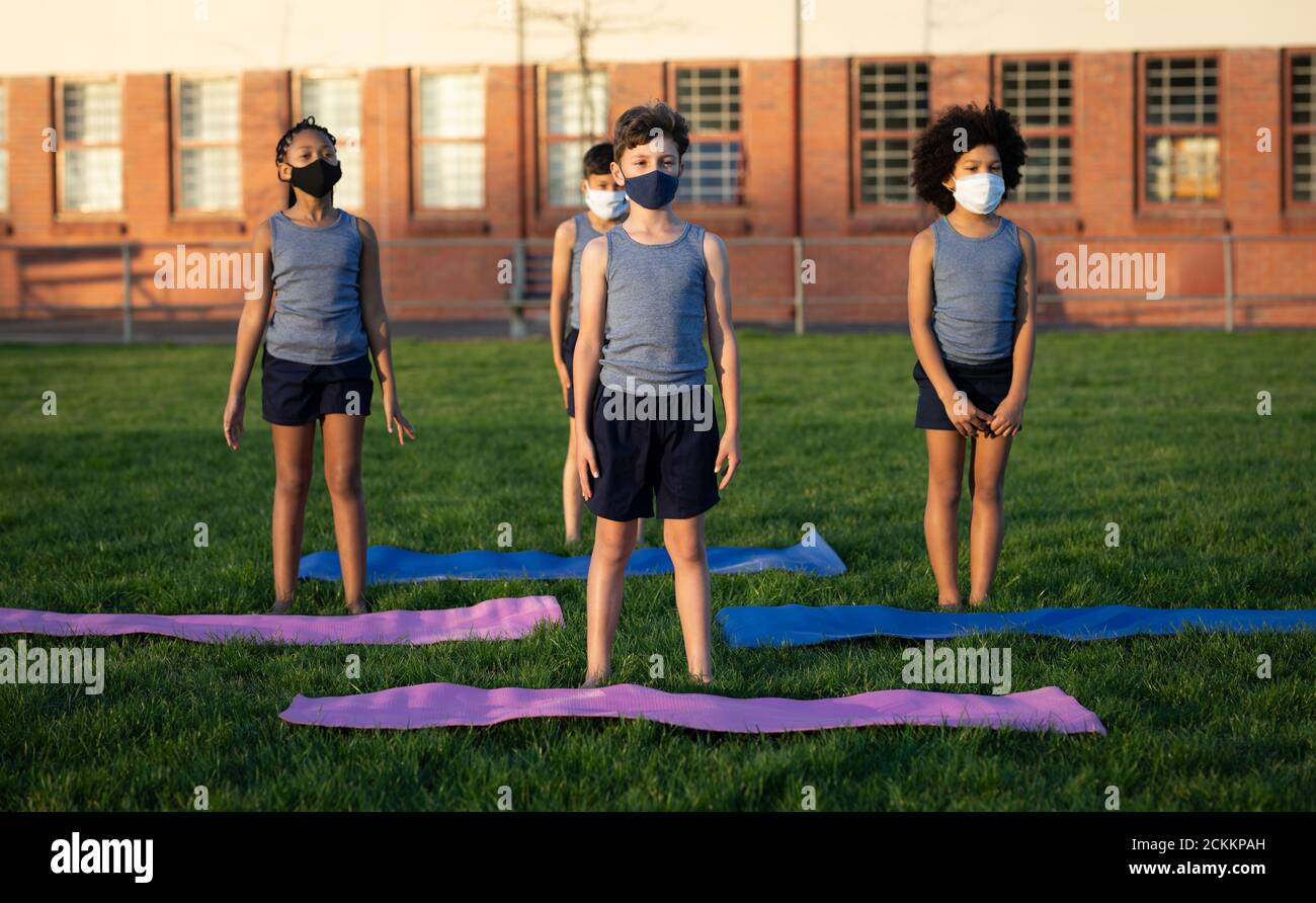 Groupe d'enfants portant des masques de yoga dans le jardin Banque D'Images