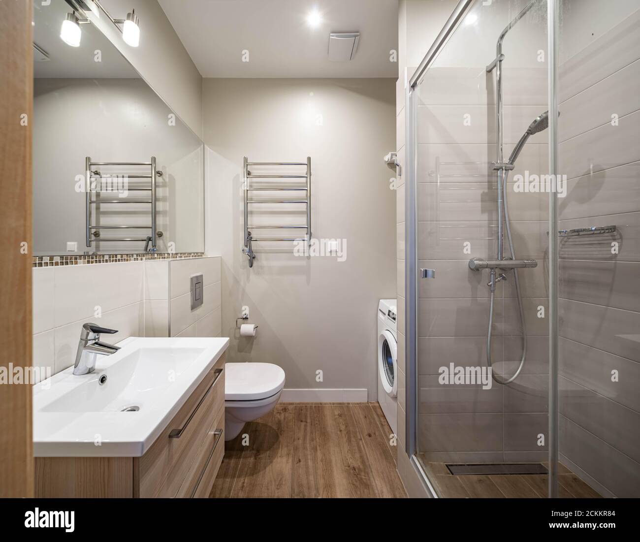 Intérieur moderne de la salle de bains dans l'appartement de luxe. Évier avec tiroirs en bois. Cabine de douche. Toilettes. Lave-linge. Banque D'Images