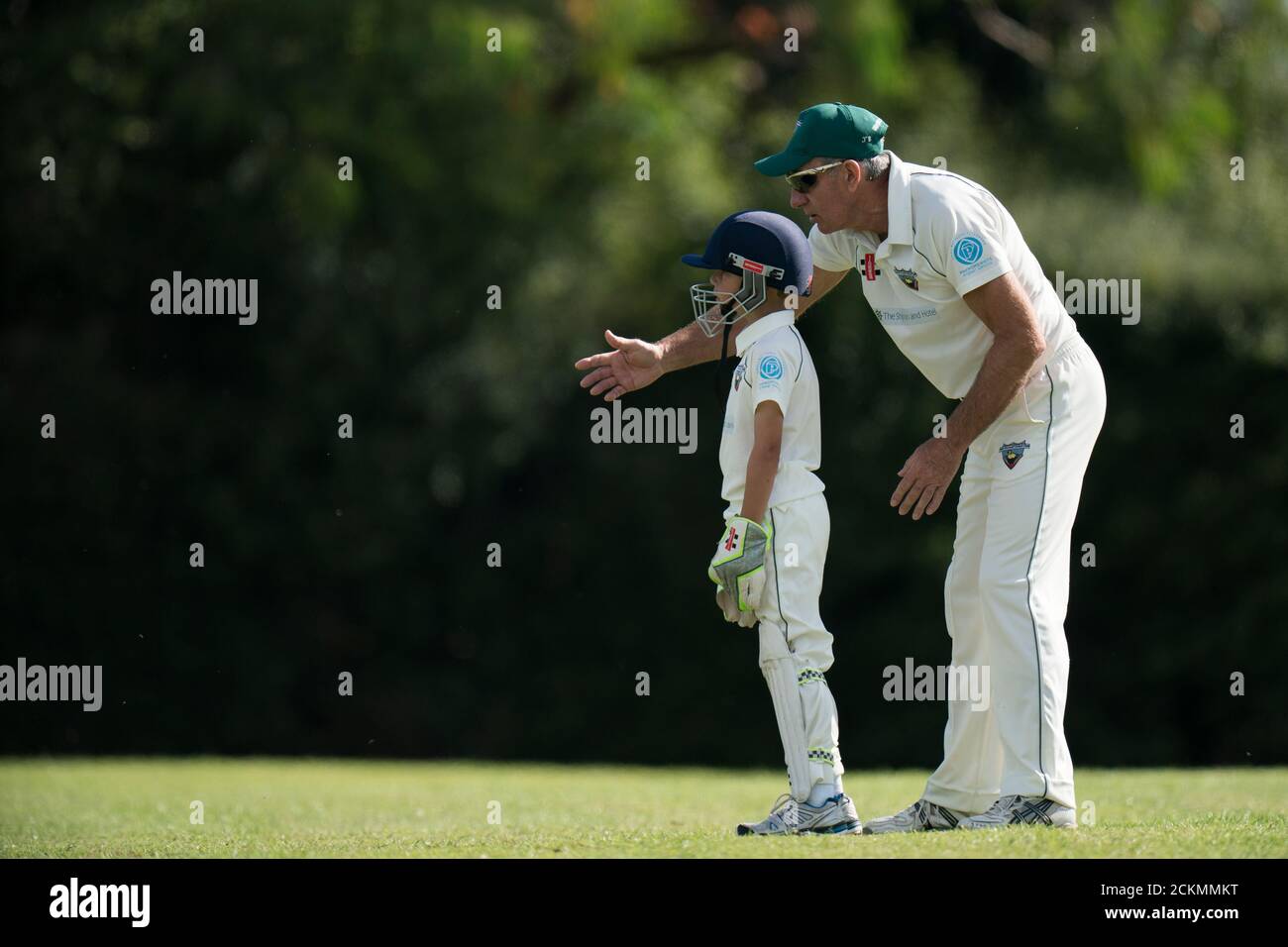 Joueur de cricket senior éduquant un jeune garçon sur la façon de garder le cricket. Banque D'Images