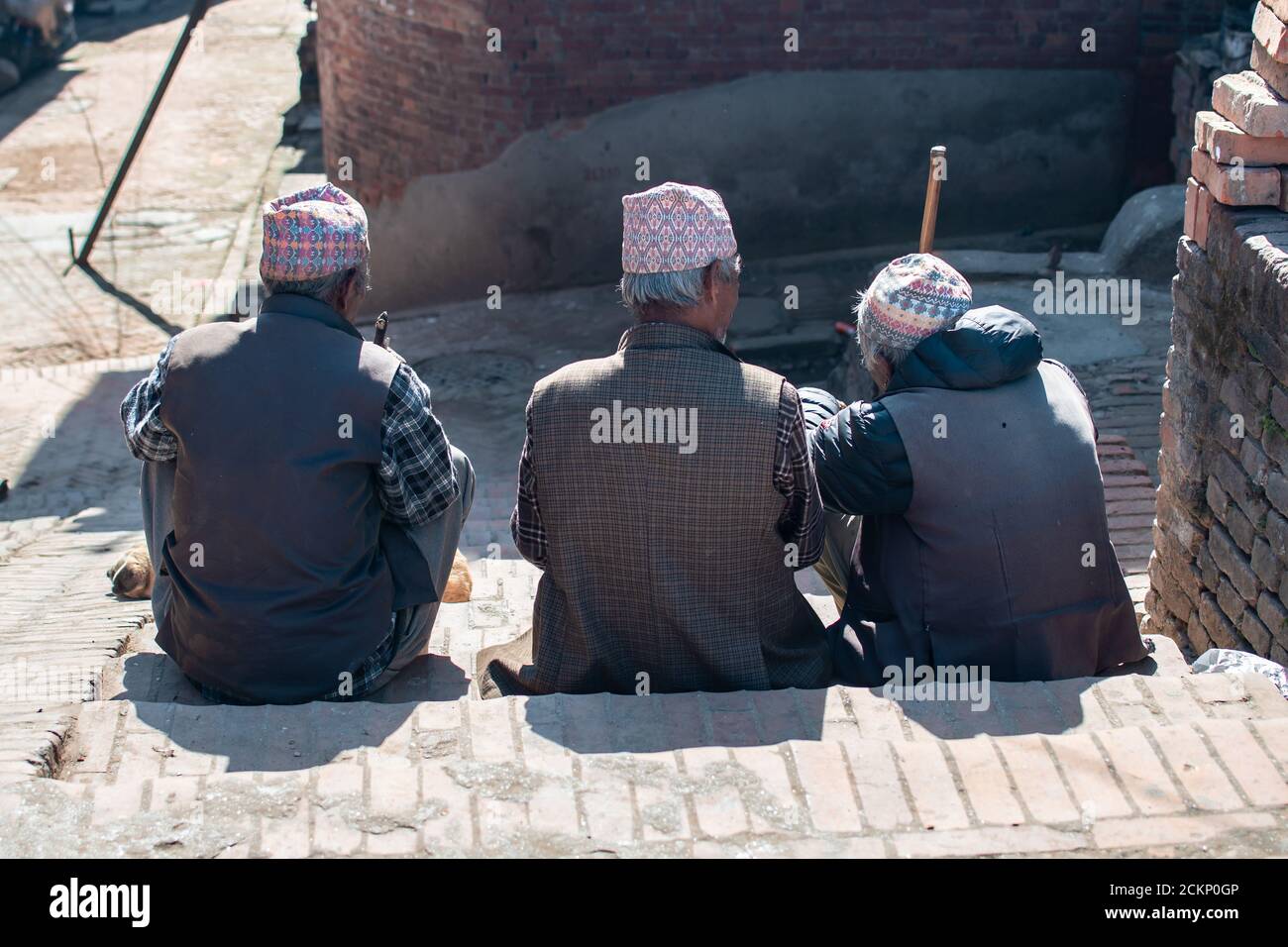 Bhaktapur, Katmandou, Népal - 23 décembre 2019 : trois hommes non identifiés sont assis et parlent sur le côté de la rue dans quelques escaliers le 23 décembre 2019 Banque D'Images