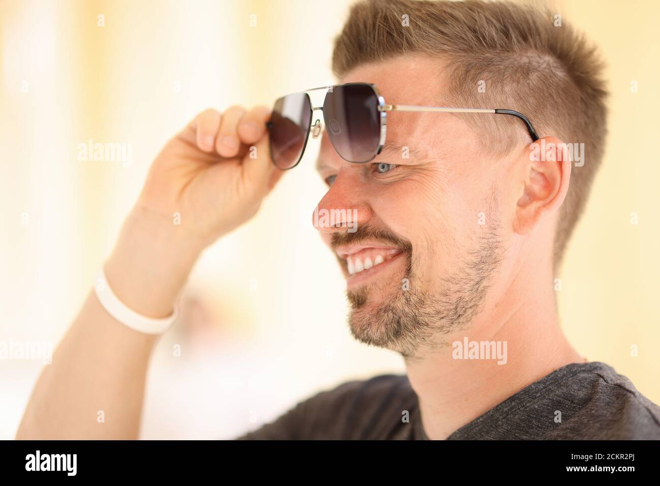 Le beau homme lève les lunettes avec sa main vers le haut de ses yeux. Banque D'Images