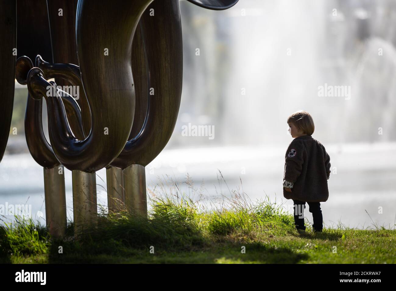 Petit garçon à côté d'une grande sculpture d'art, fontaine derrière Banque D'Images
