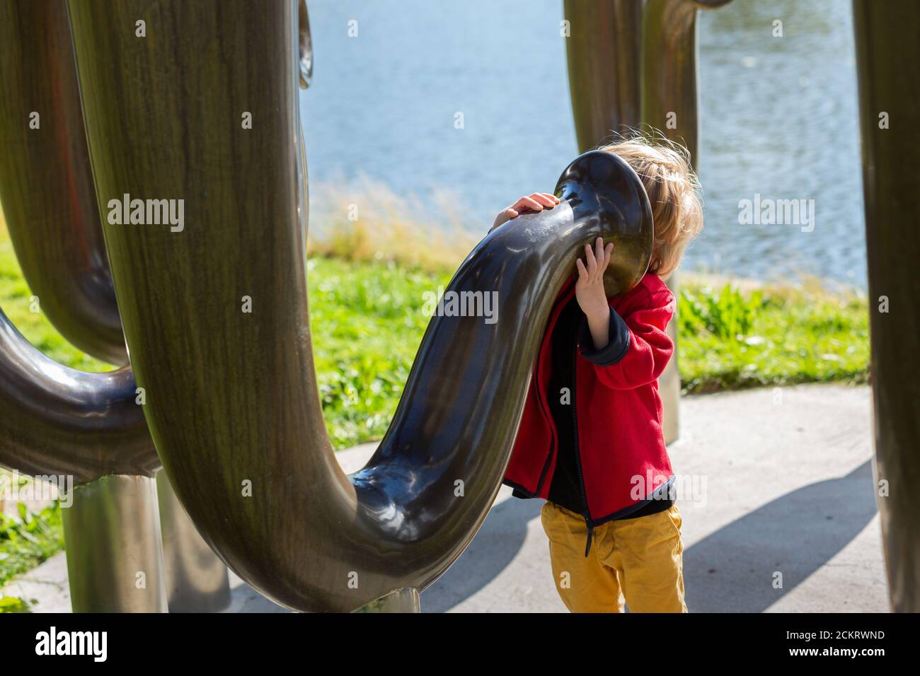 jeune garçon regardant dans une grande sculpture ressemblant au tuba instruments à vent Banque D'Images