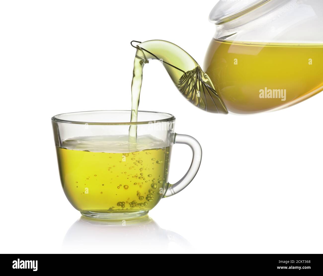 Le thé coule de la théière dans une tasse en verre isolée en blanc Banque D'Images