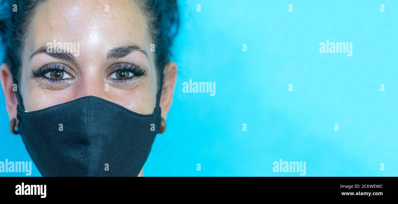 jeune femme souriante avec masque de protection médical noir. fond bleu. espace de copie Banque D'Images