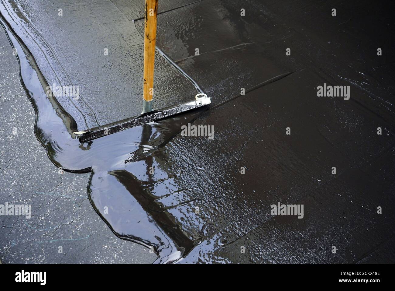 Homme scellant l'allée d'asphalte/enduit d'étanchéité Banque D'Images