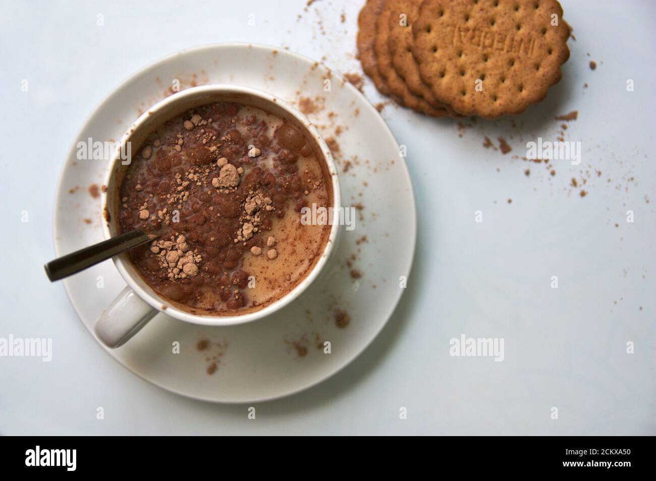 Vue de dessus d'une table où nous voyons un bol de lait avec cacao soluble à côté d'un peu de grain entier cookies Banque D'Images