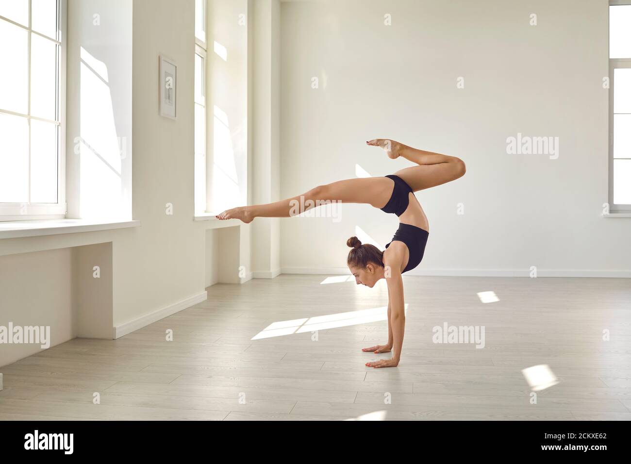 Fille gardant l'équilibre sur les mains et pratiquant la gymnastique rythmique Banque D'Images