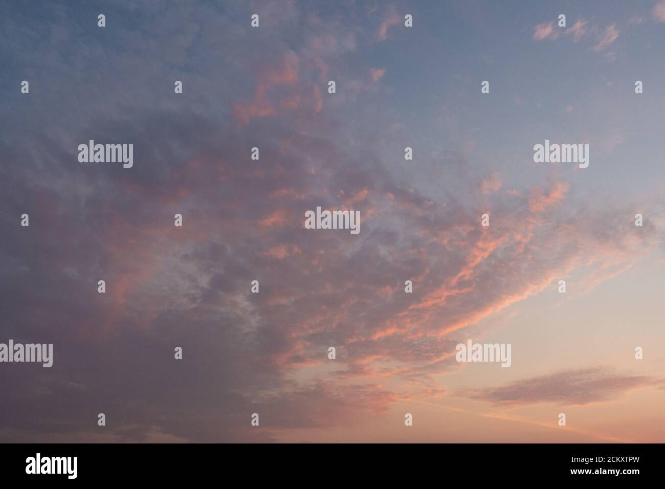 Des nuages spectaculaires de coucher de soleil avec des teintes roses et oranges à travers le ciel du soir Banque D'Images Des nuages spectaculaires de coucher de soleil avec des teintes roses et oranges à travers le ciel du soir Banque D'Images