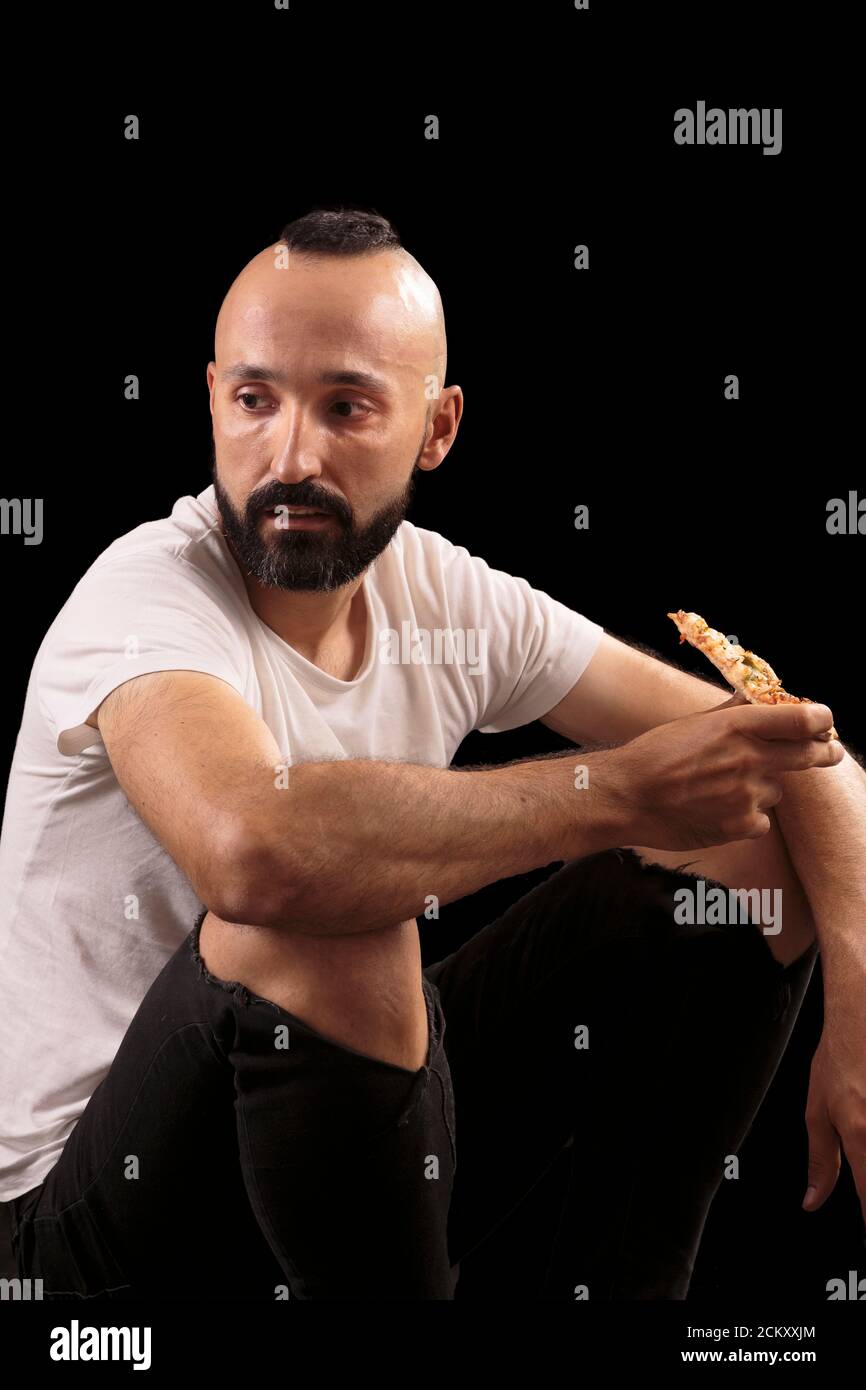 Jeune ouvrier de construction hispanique mangeant de la pizza Banque D'Images
