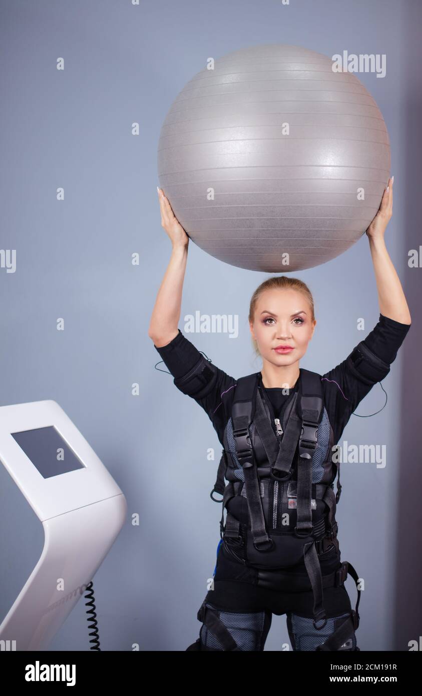 Blonde fille portant un costume électrique de stimulation musculaire faire  de l'exercice avec le ballon dans la salle de gym. Sport et bien-être  concept. Gros plan photo Photo Stock - Alamy