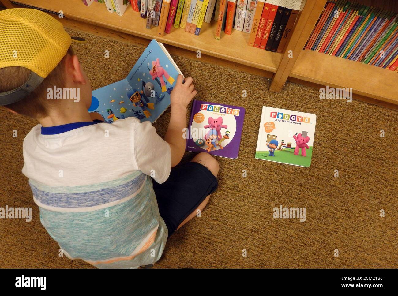 Un jeune garçon lisant des livres par terre. Banque D'Images