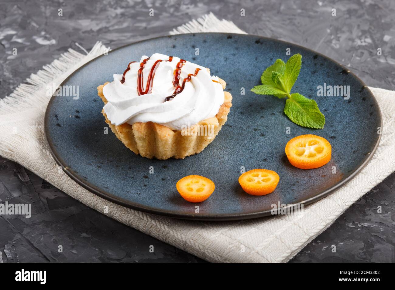 Gateau A La Creme Fouettee Aux œufs Sur Une Assiette En Ceramique Bleue Avec Des Tranches De Kumquat Et Des Feuilles De Menthe Sur Un Fond En Beton Noir Avec Serviette En