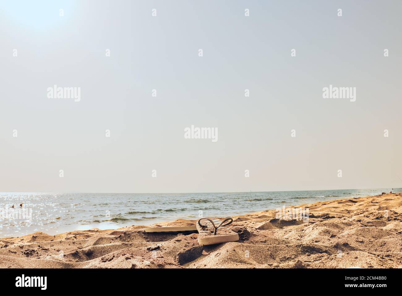 Plage d'été à la mer avec des tongs sur un jaune sable Banque D'Images