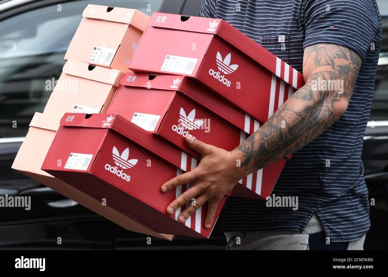 Un homme porte des boîtes à chaussures Adidas près du magasin Adidas, comme  la propagation de la maladie du coronavirus (COVID-19) continue, à Berlin,  Allemagne, le 25 avril 2020. REUTERS/Annegert Hilse Photo