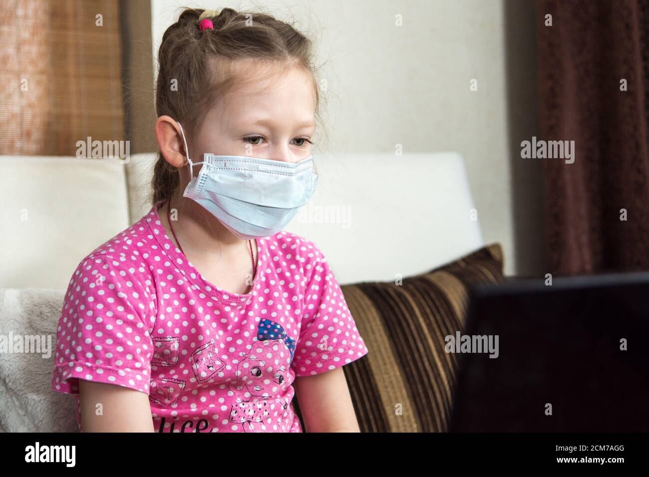Enseignement en ligne à distance. Écolière portant un masque protecteur en quarantaine étudiant à la maison avec un ordinateur portable et faisant des devoirs à l'école. Coronavir Banque D'Images