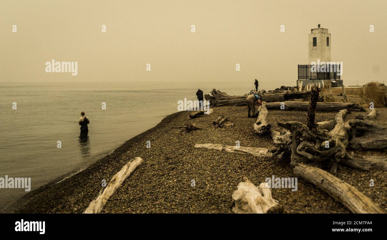 Pêcheurs dans le détroit de Puget près du phare de Bown's point dans le brouillard de feu de forêt Banque D'Images