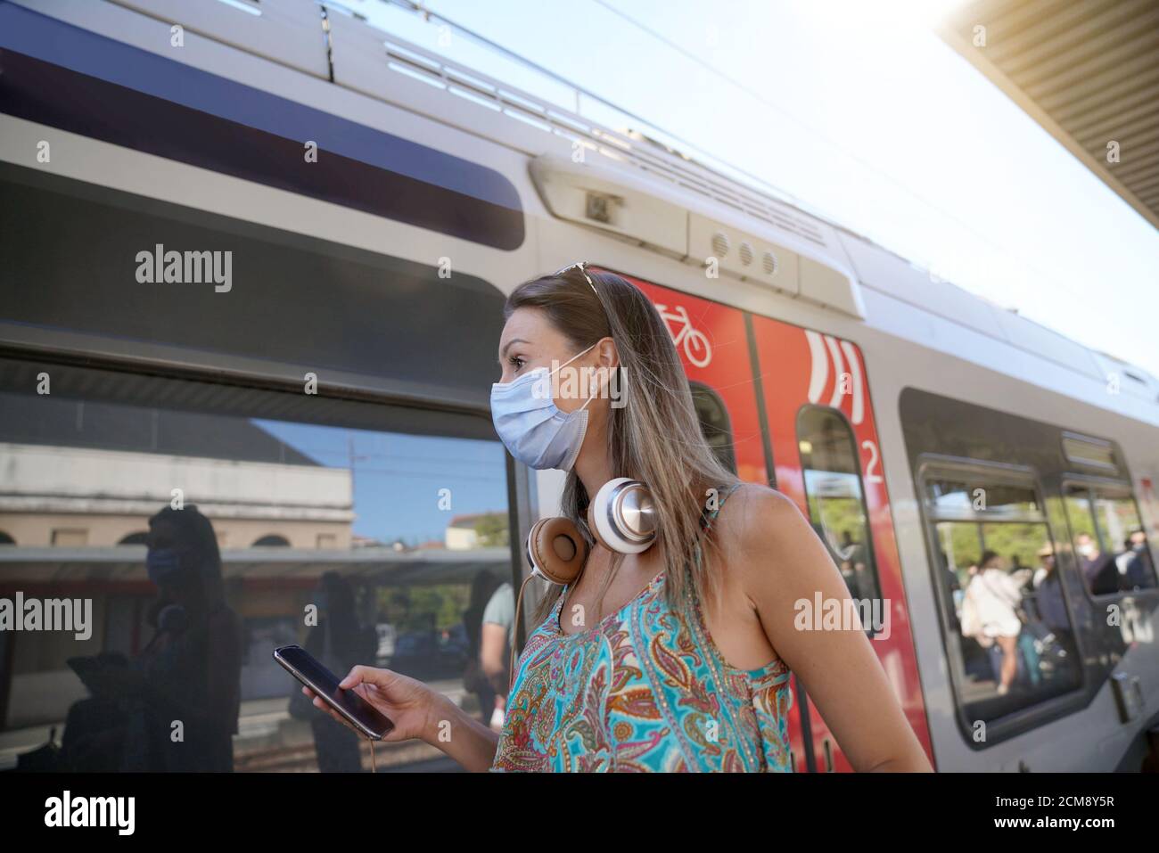 Jeune femme attendant le train sur la plate-forme de chemin de fer, portant un masque facial Banque D'Images