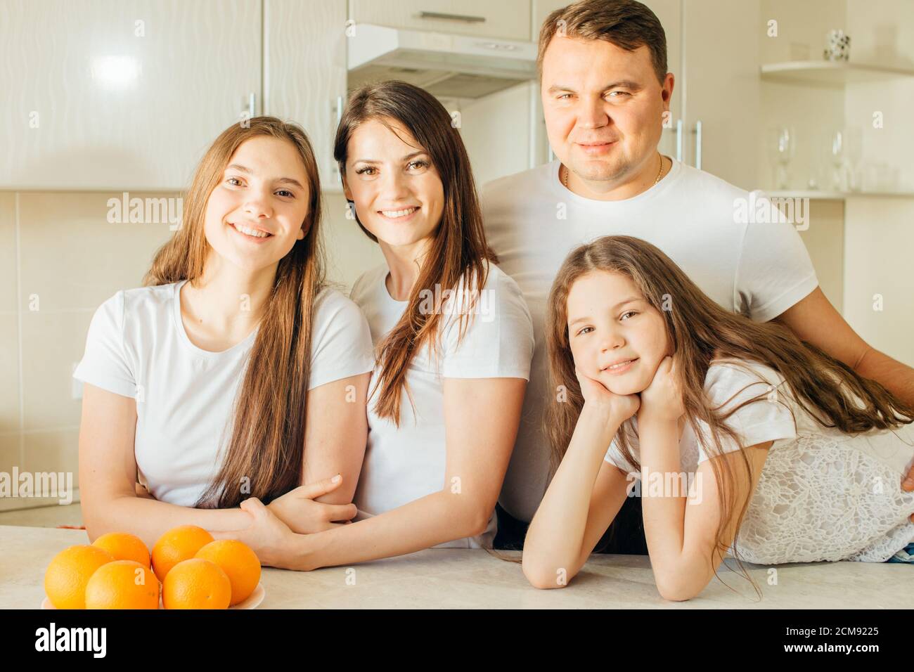 Portrait de famille regardant l'appareil photo tout en cuisinant dans la cuisine Banque D'Images