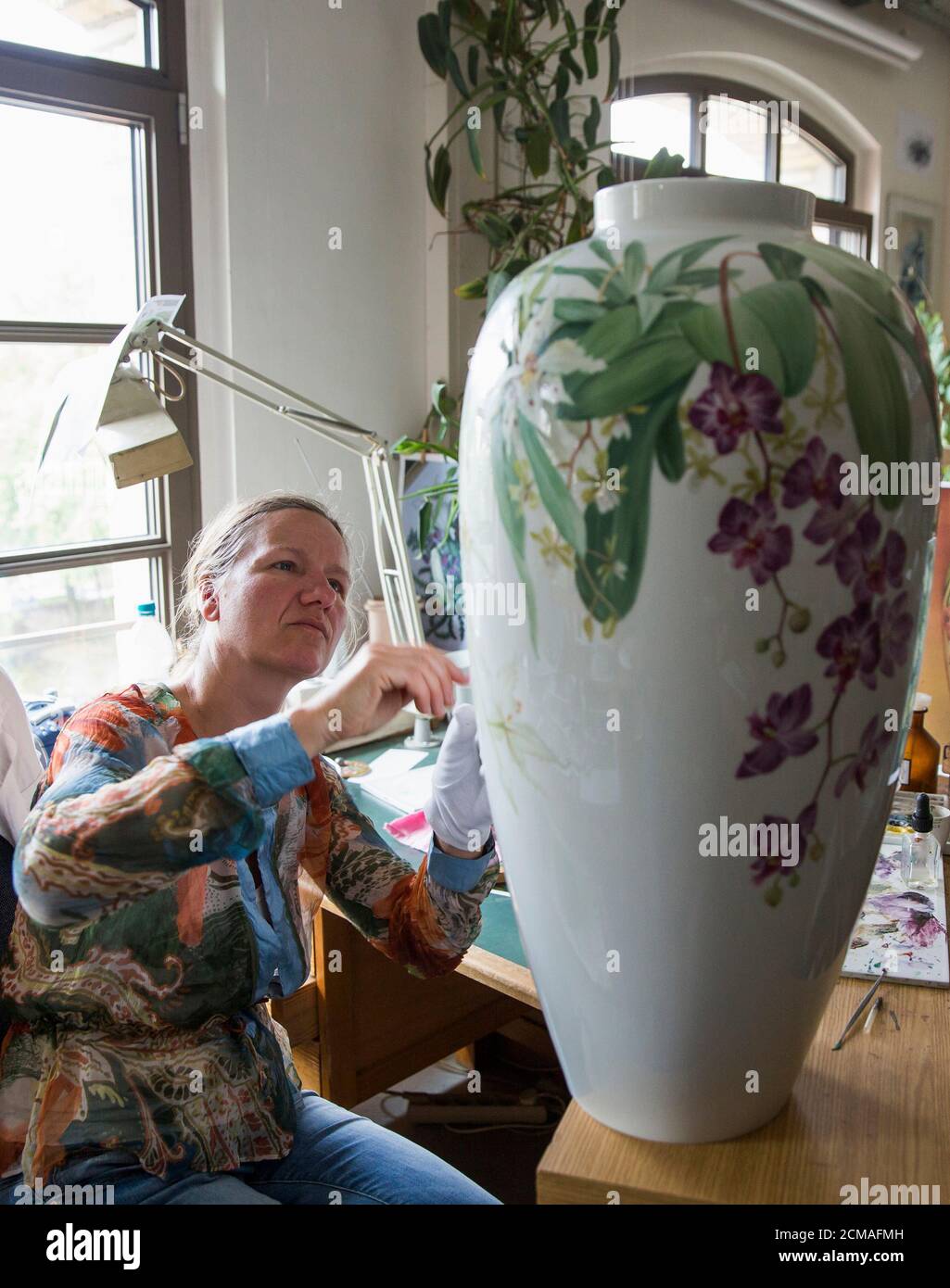A woman paints on a vase at the KPM porcelain manufacturer in Berlin June  28, 2013. A recent study by consulting firm Ernst & Young showed three of  every four German Mittelstand