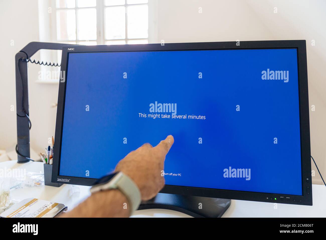Paris, France - 7 septembre 2020 : la main mâle POV pointant vers le grand moniteur de référence NEC Spectraview présentant ceci peut prendre plusieurs minutes de texte pendant la mise à jour de l'écran bleu de Microsoft Windows Banque D'Images