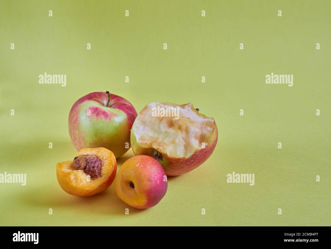 Les pommes et nectarines entières et grignotées reposent sur un fond coloré. Gros plan Banque D'Images
