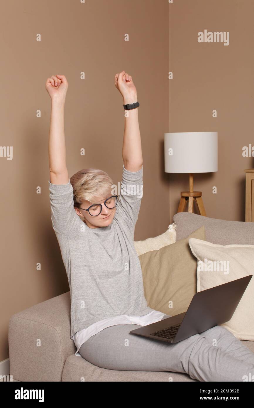 Jeune femme excitée célébrant ses réalisations et gagne avec ses mains vers le haut. Jolie femme intelligente environ 30s dans des vêtements décontractés et des lunettes avec les genoux Banque D'Images