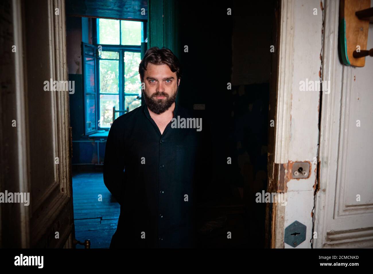 Portrait de l'homme charismatique aux yeux bleus barbu avec un regard à l'intérieur du bâtiment abandonné Banque D'Images