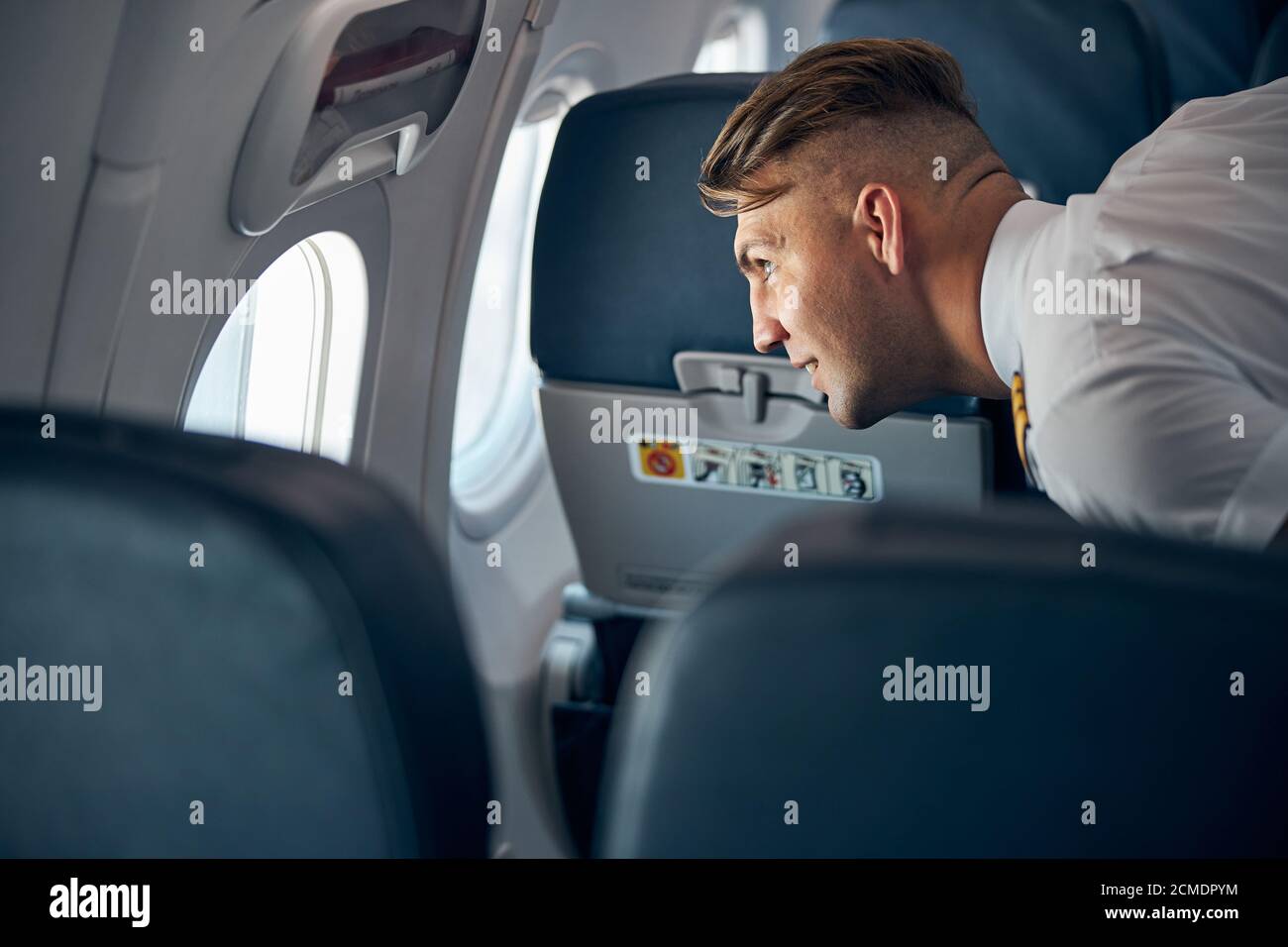 Homme souriant en uniforme debout à l'illuminateur dans l'avion Banque D'Images