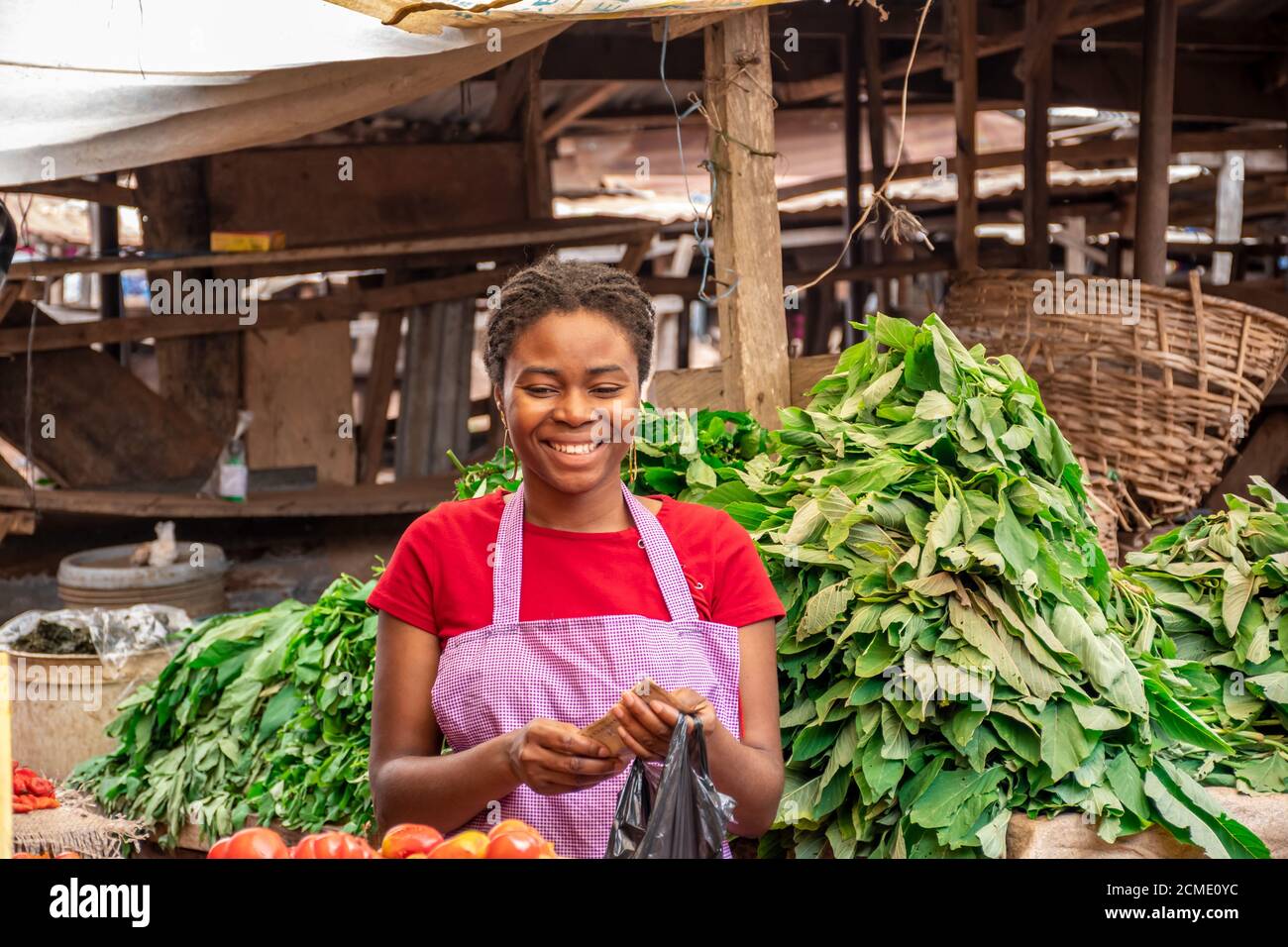 portrait d'une femme africaine souriante qui vend dans un local marché africain Banque D'Images