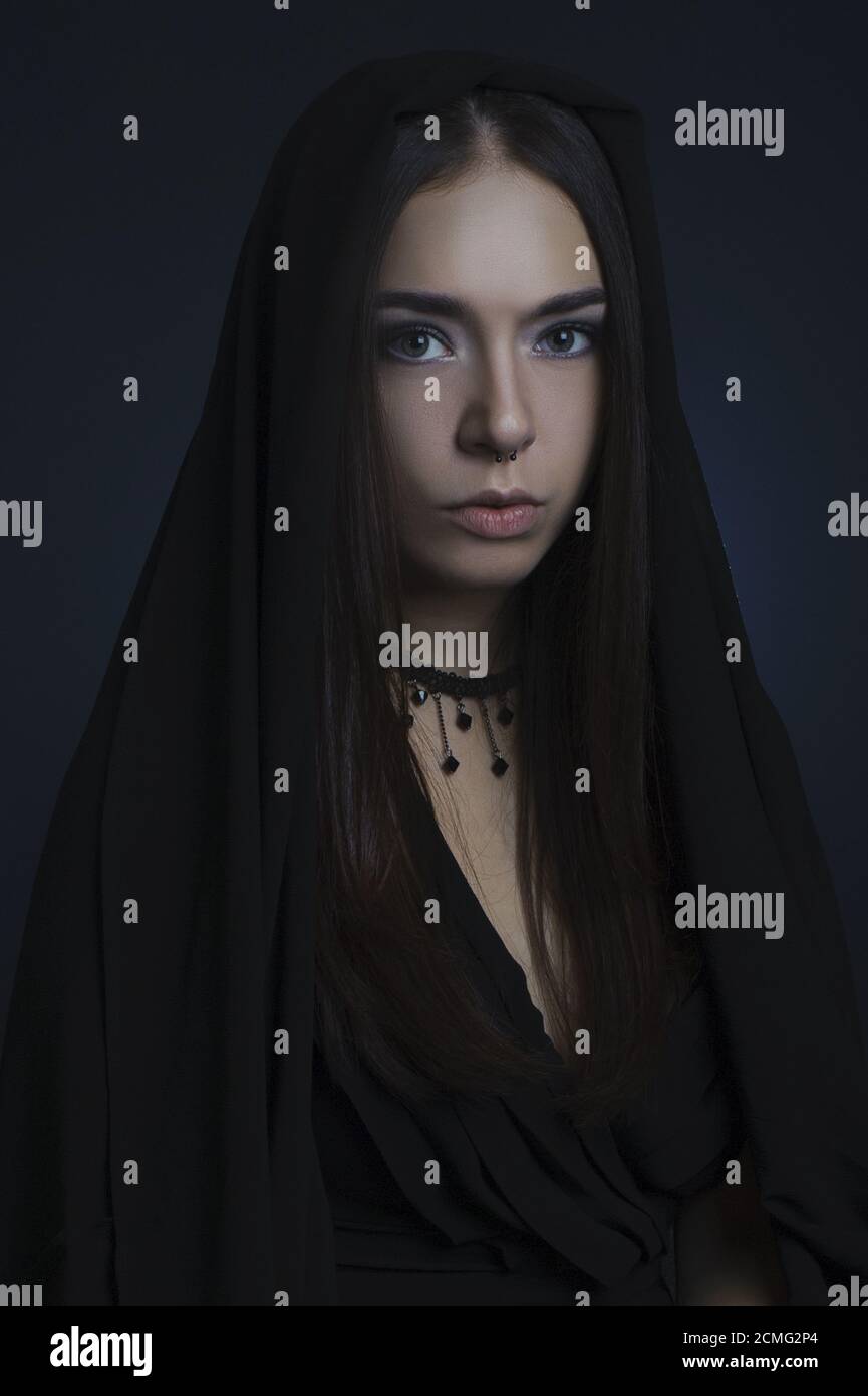 Portrait d'une fille dans une robe noire avec sa tête couverte. Banque D'Images