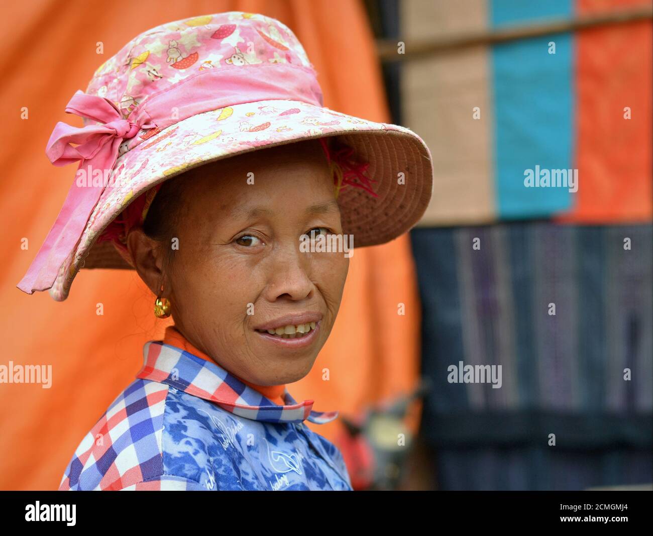 La femme âgée de la tribu des collines de Hmong, une minorité ethnique vietnamienne, porte un chapeau de soleil moderne en rose et sourit pour la caméra. Banque D'Images
