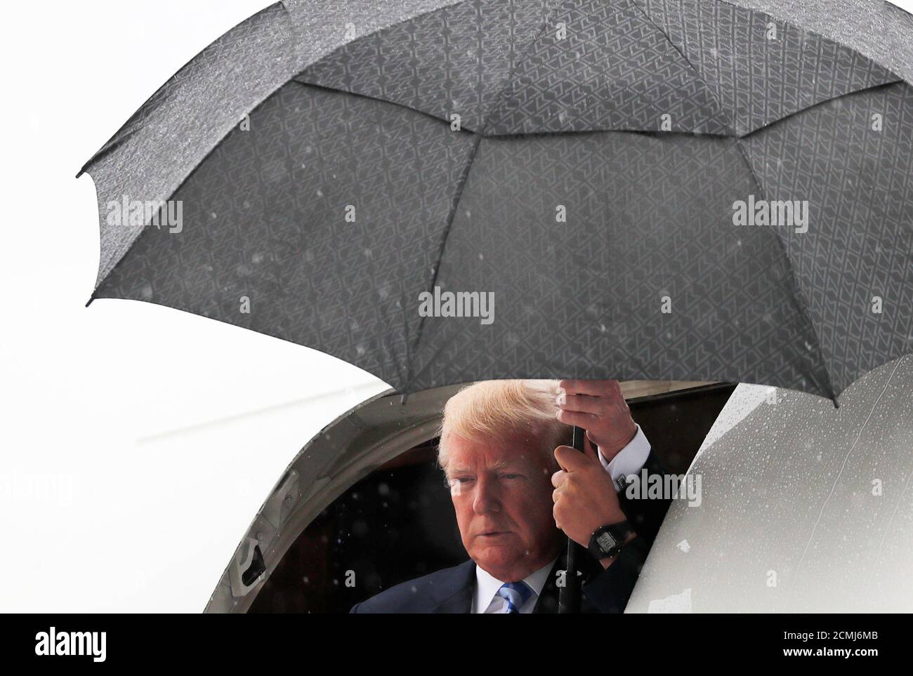 Le président américain Donald Trump quitte Air Force One en tant qu'aide  tient un parapluie en hauteur tout en arrivant à Dallas Love Field sous la  pluie pour s'adresser à la Convention