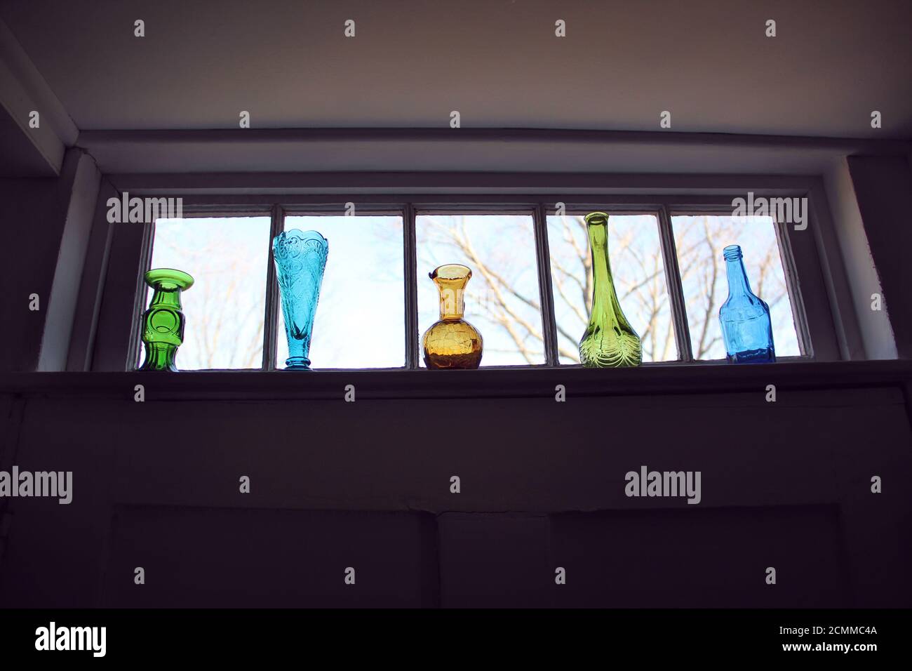 Vases en verre de couleur vintage dans une rangée sur une fenêtre seuil Banque D'Images