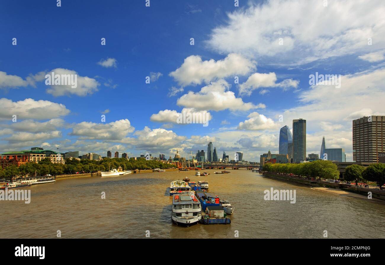 Vue panoramique sur la Tamise avec divers bâtiments emblématiques et barges contre un ciel bleu ciel nuageux Banque D'Images