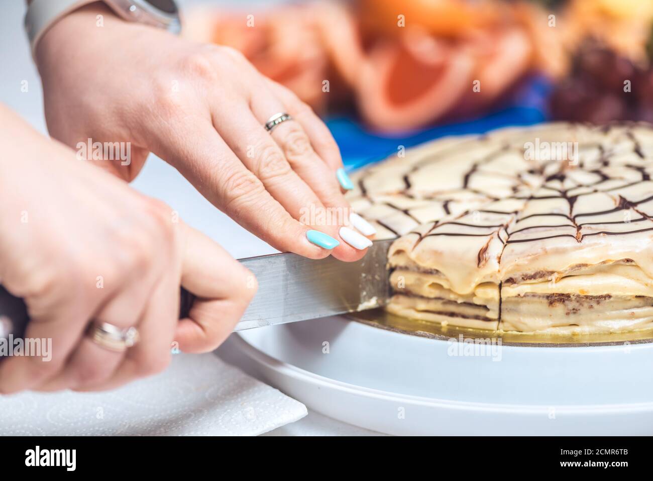 Les mains de la femme coupent le gâteau complet de la torte d'esterhazy avec un couteau. Recette authentique, dessert hongrois et autrichien, vue d'en haut, clos Banque D'Images