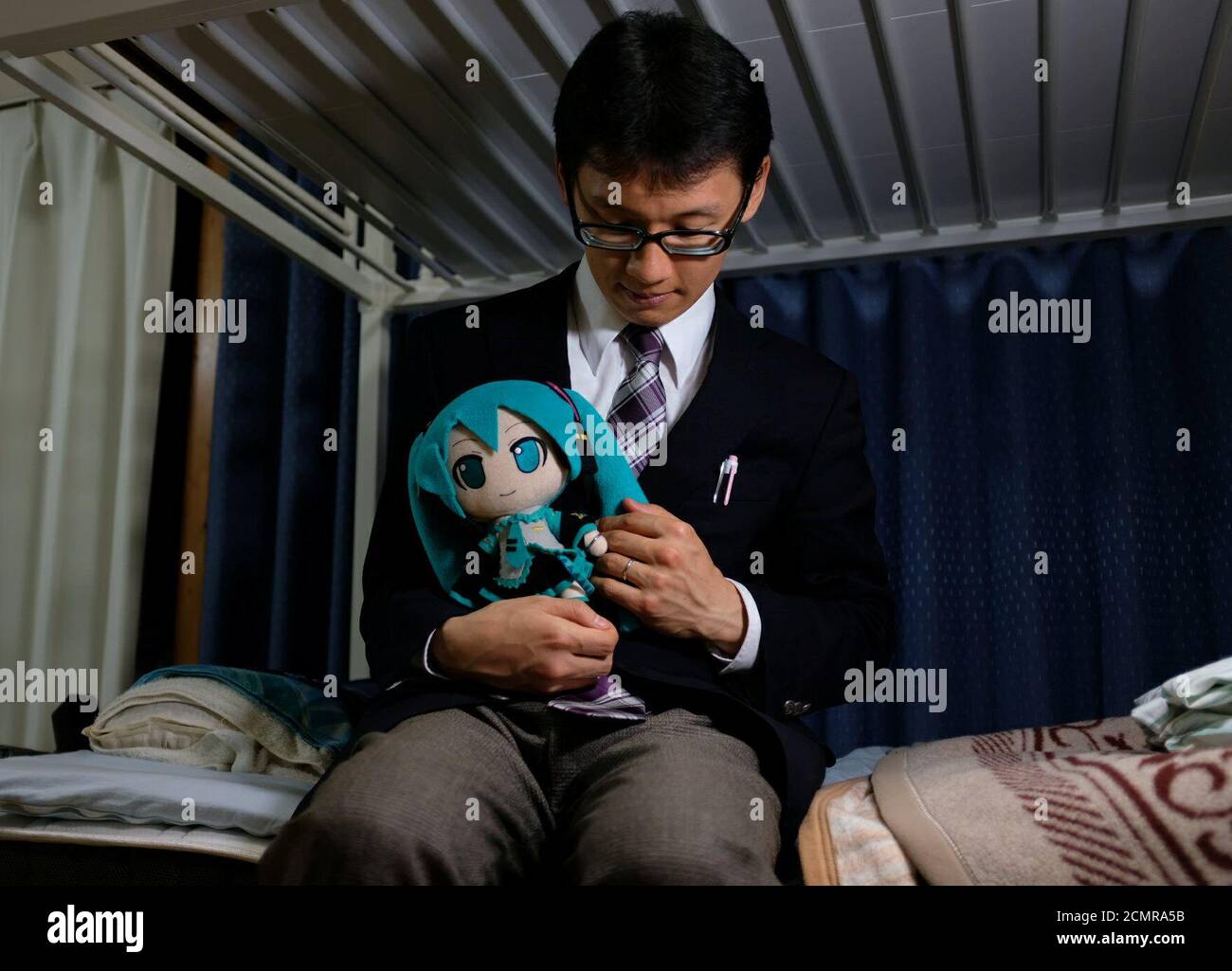 Akihiko Kondo, 35 ans, pose pour une photo avec une poupée modelée d'après  la chanteuse de réalité virtuelle Hatsune Miku, portant leurs anneaux de  mariage, dans son appartement après l'avoir épousé à