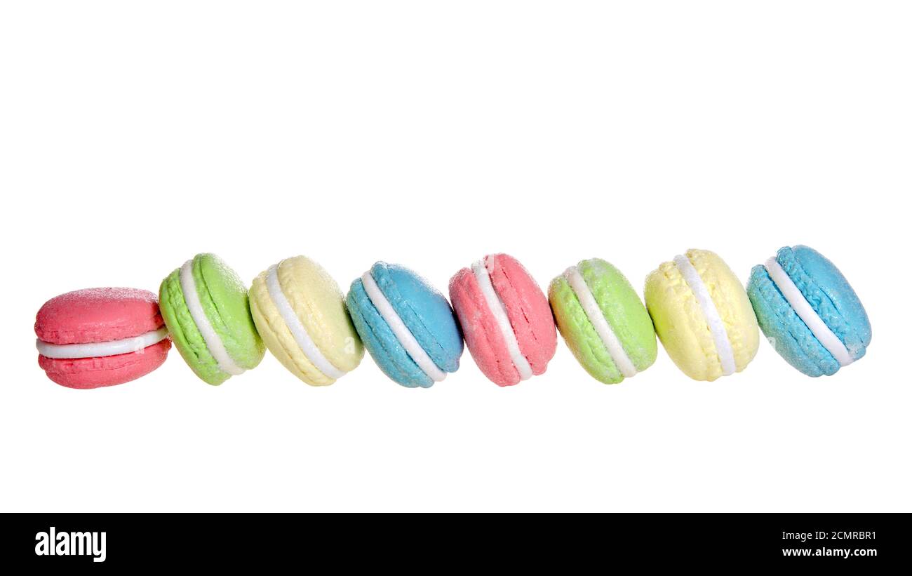 Rangée de biscuits macaron posés côte à côte de multiples couleurs pastel et saveurs isolées sur le blanc. Régal français traditionnel. Banque D'Images