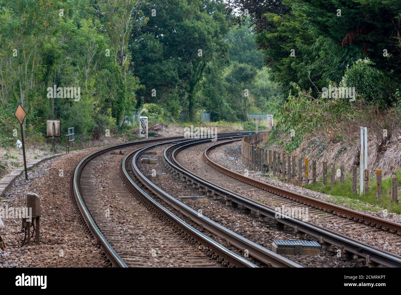 une voie de chemin de fer qui se courbe dans la distance et qui disparaît avec des rails et des lignes qui s'effile à travers l'image. Banque D'Images