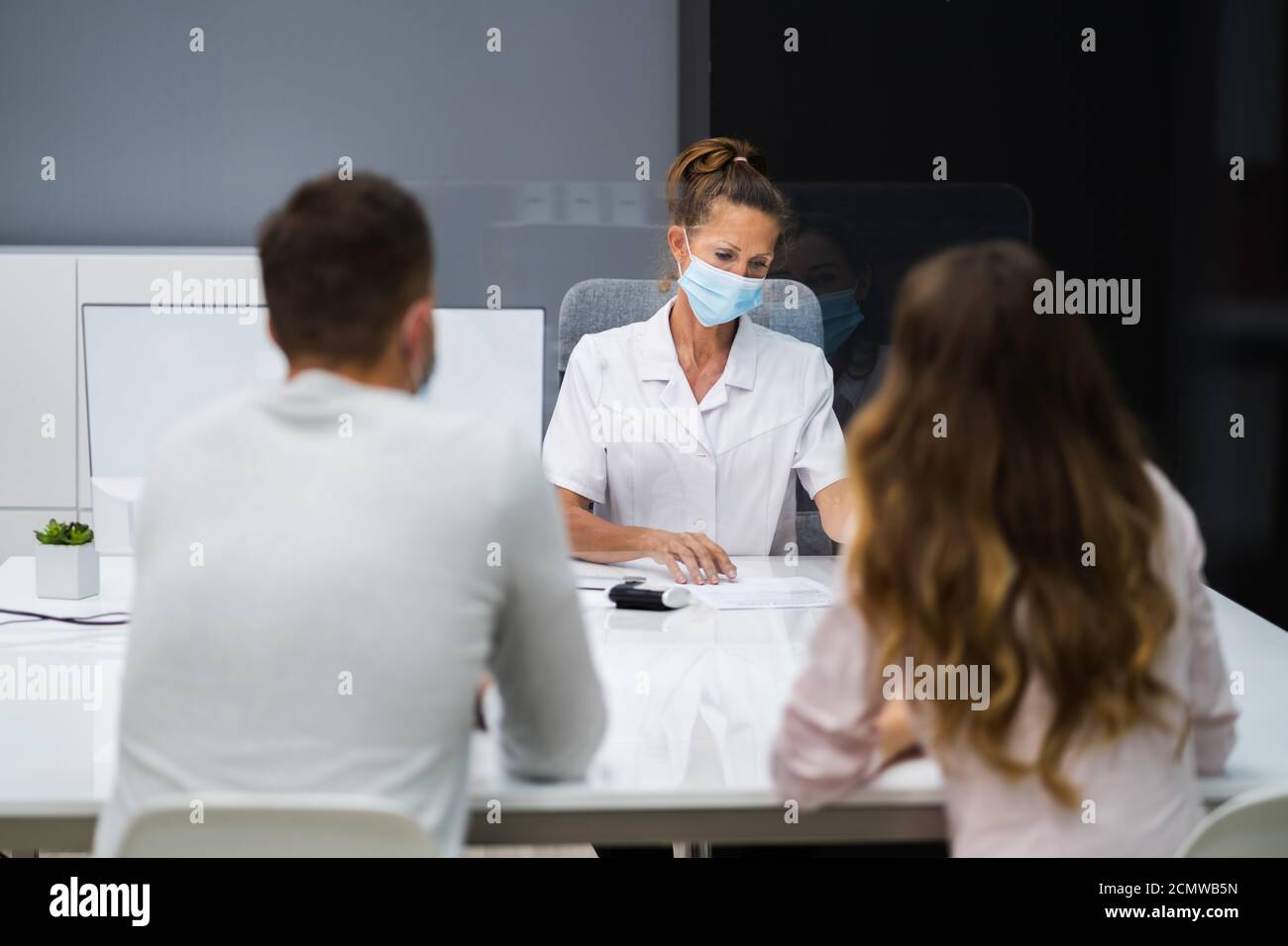 Médecin parlant au patient lors de la réunion au sujet de la grossesse avec le visage Masques Banque D'Images