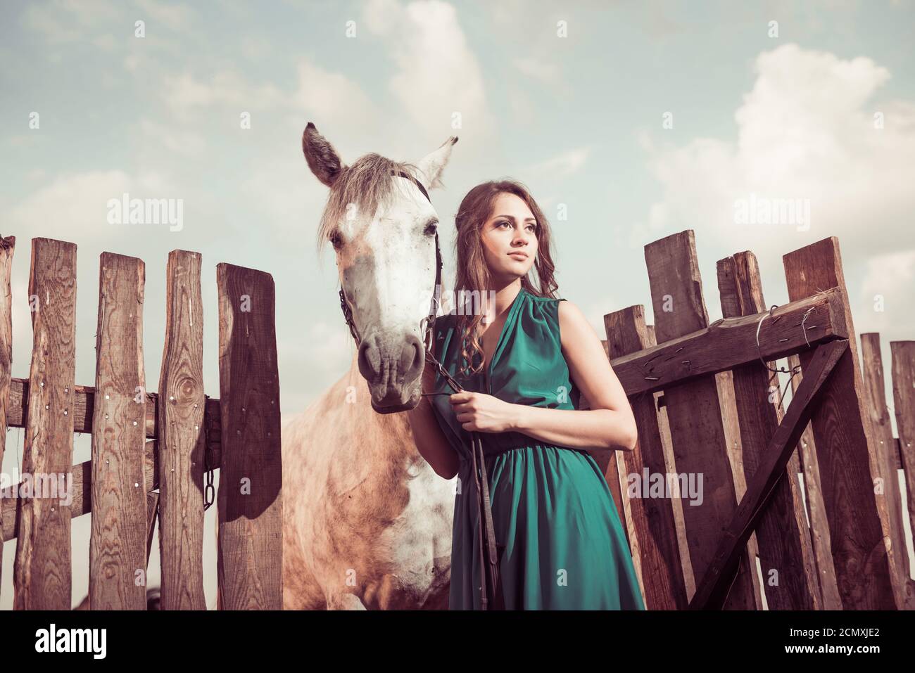 femme en robe verte élégante et cheval blanc à la campagne clôture en bois de la ferme Banque D'Images