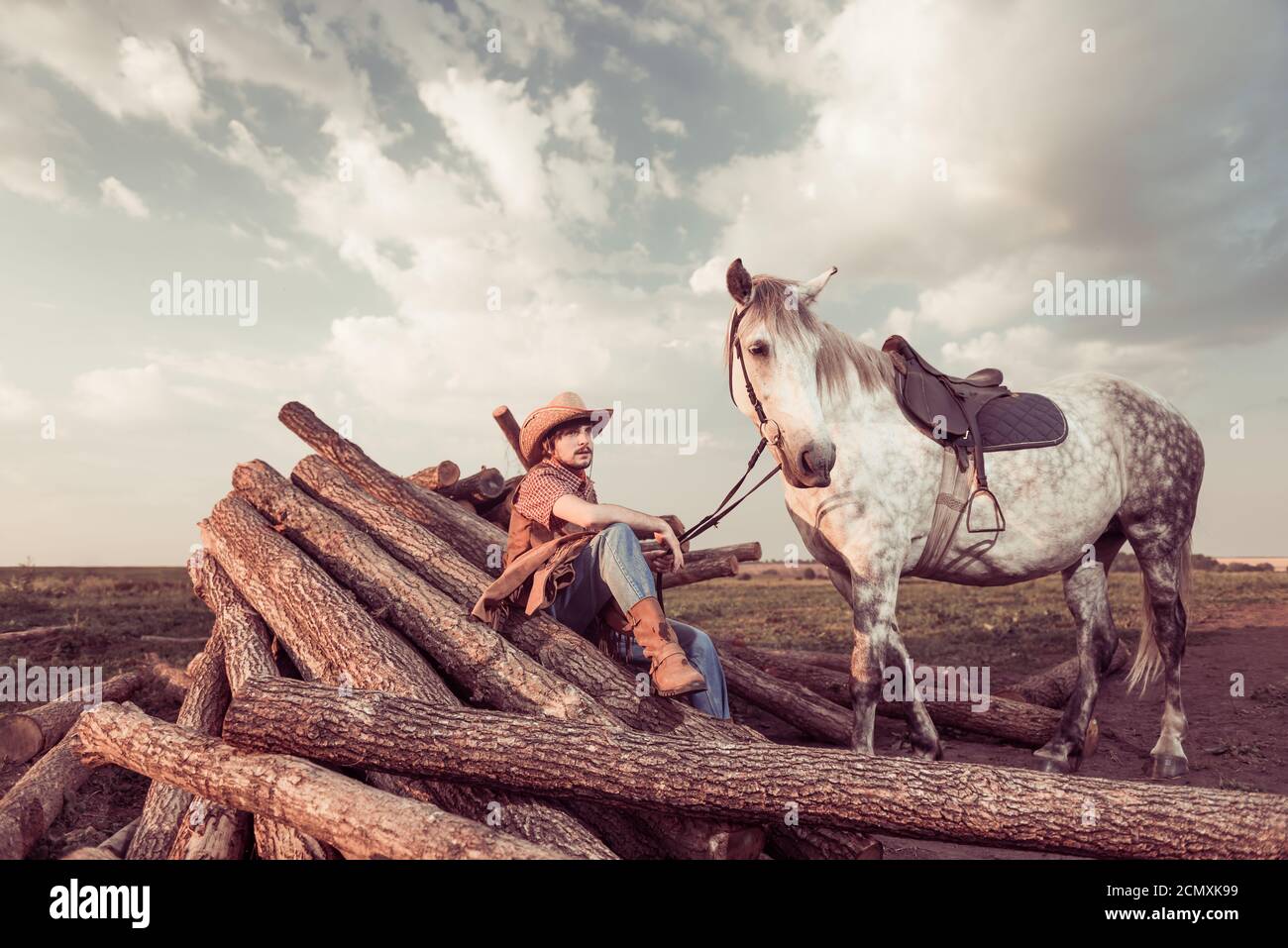 jeune cow-boy beau avec cheval sur les terres agricoles Banque D'Images
