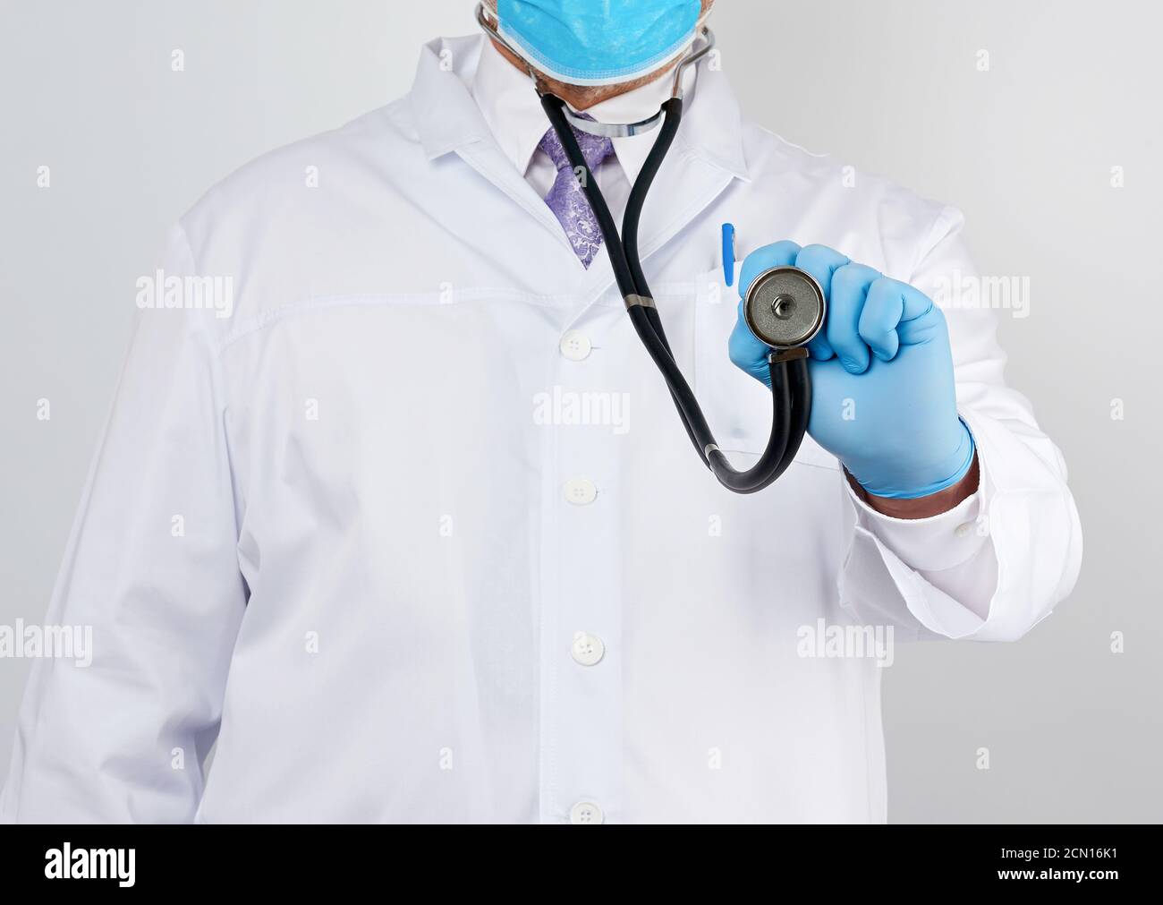 docteur dans un manteau blanc et cravate tient dans son main un phonendoscope noir Banque D'Images