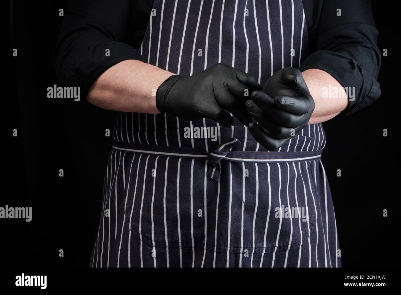 chef homme en uniforme noir et à rayures tablier robes latex gants Banque D'Images