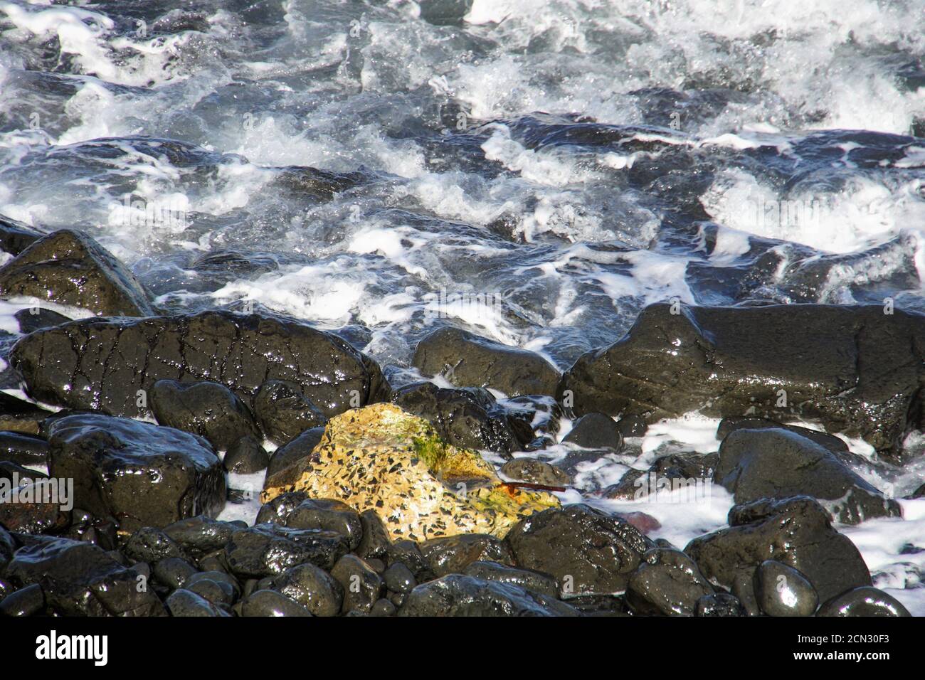 De l'eau s'inclant sur des galets humides et brillants Banque D'Images